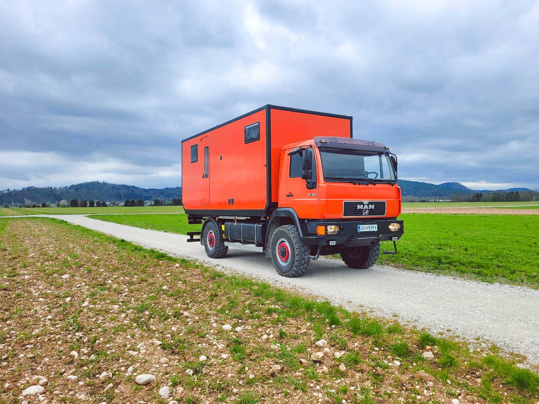 Orange MAN expedition truck on a rural road